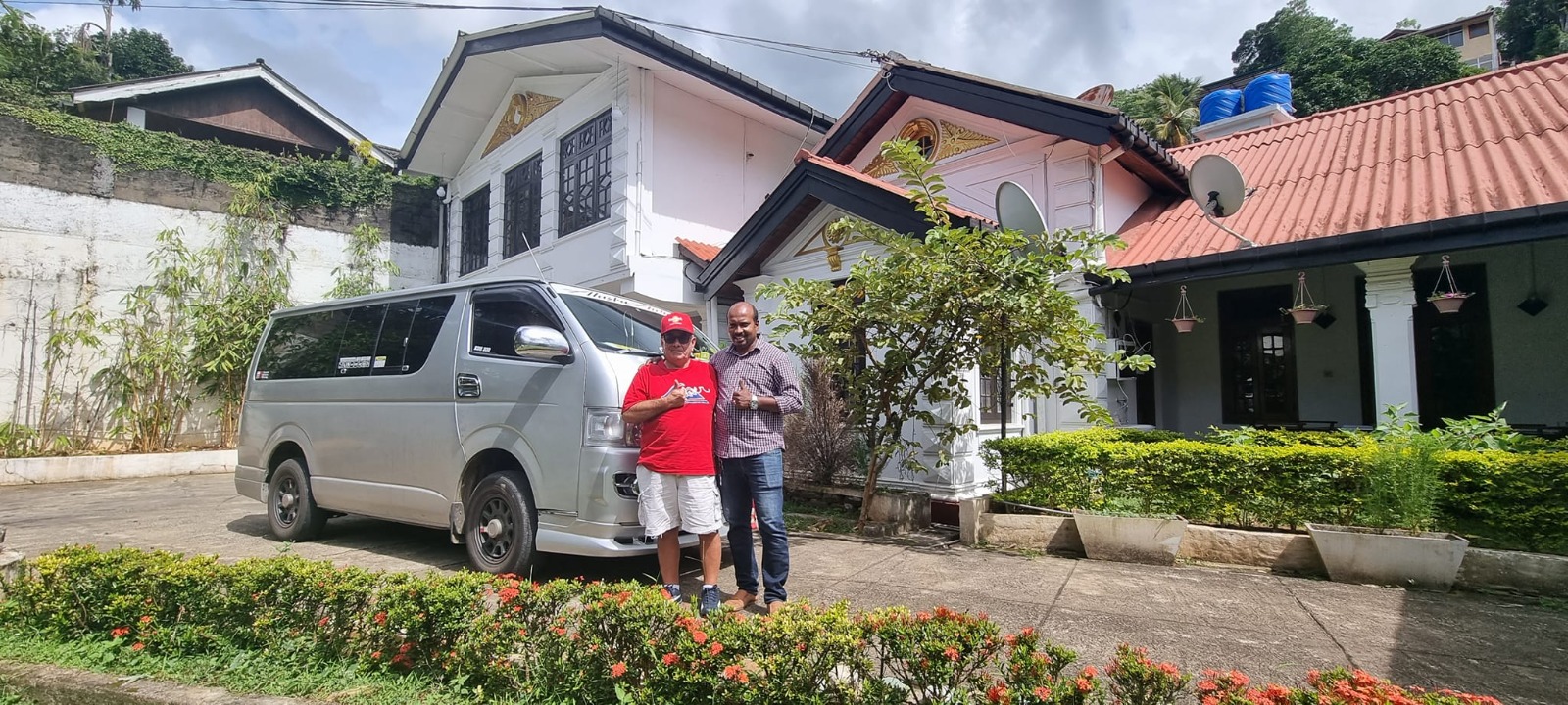 Travellers beside a tour van outside a guesthouse