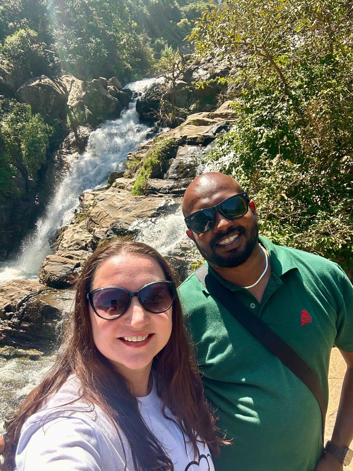 Two travellers taking a selfie beside a waterfall