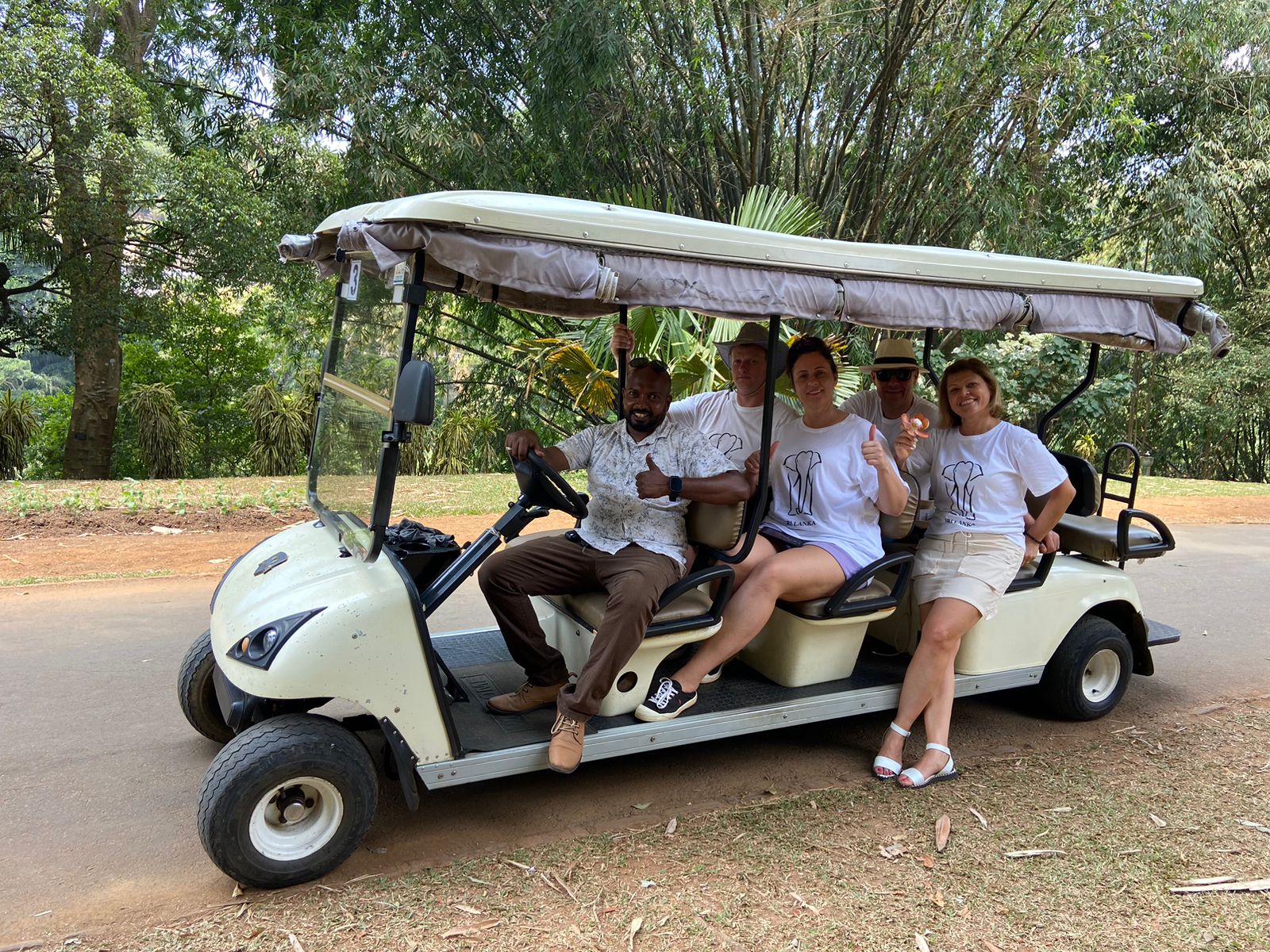 Travellers riding a golf cart through tropical gardens