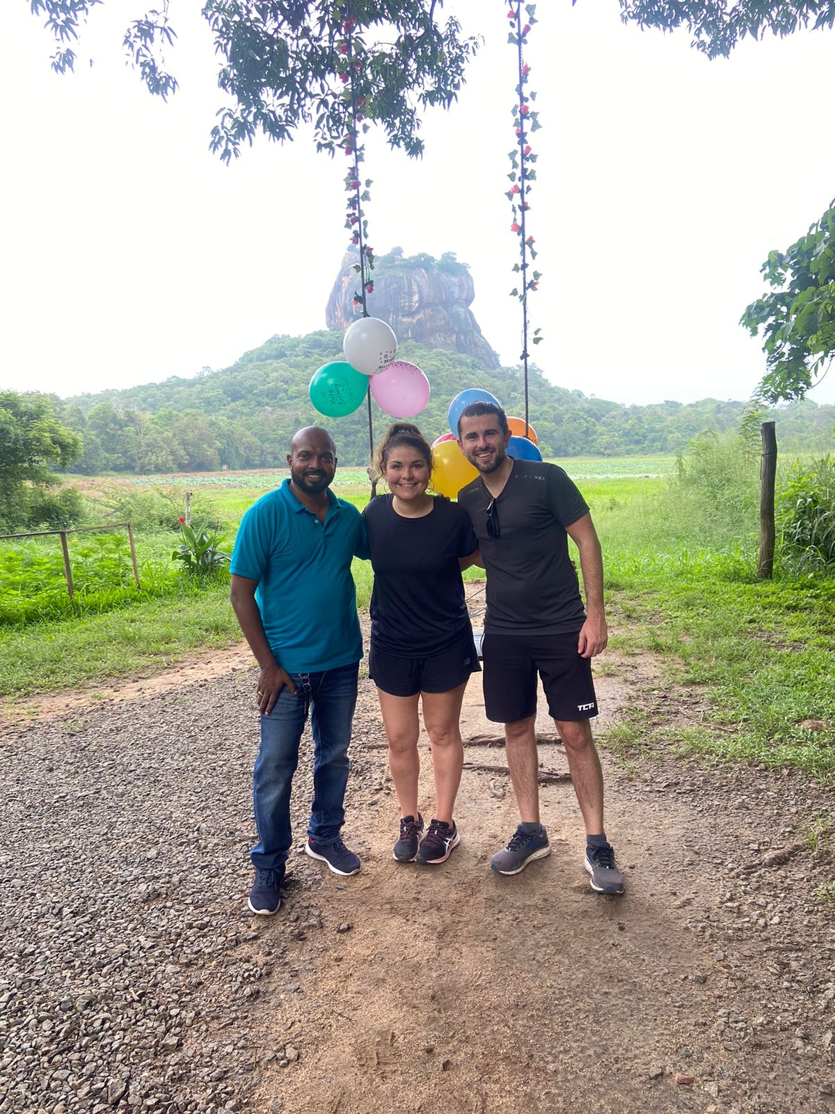 Travellers standing on a path with Sigiriya in the distance