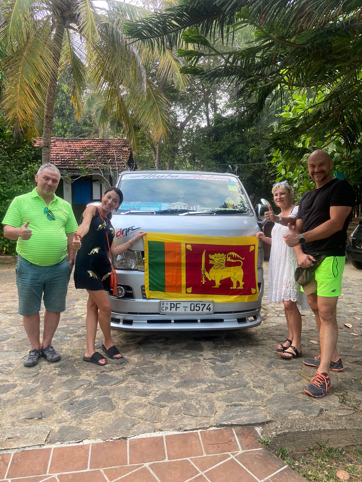 Travellers holding a Sri Lankan flag beside a vehicle