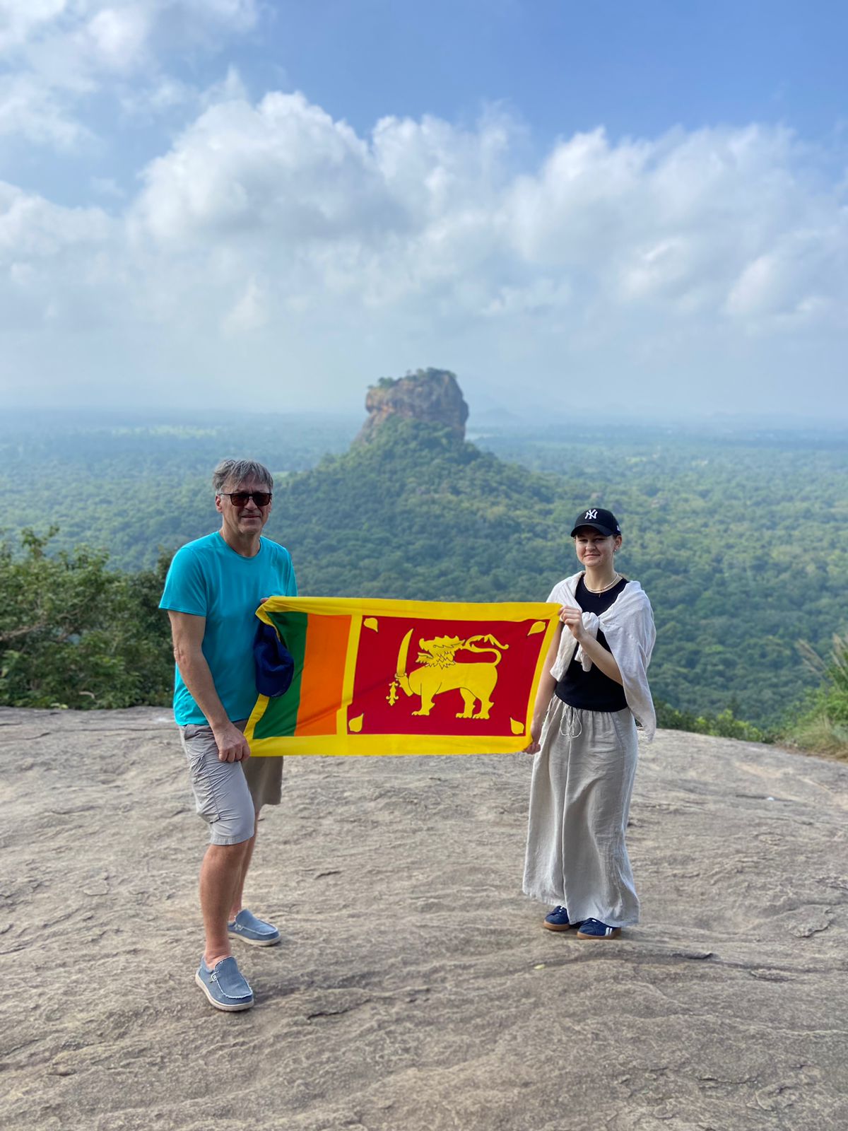 Two travellers holding a Sri Lankan flag at a viewpoint