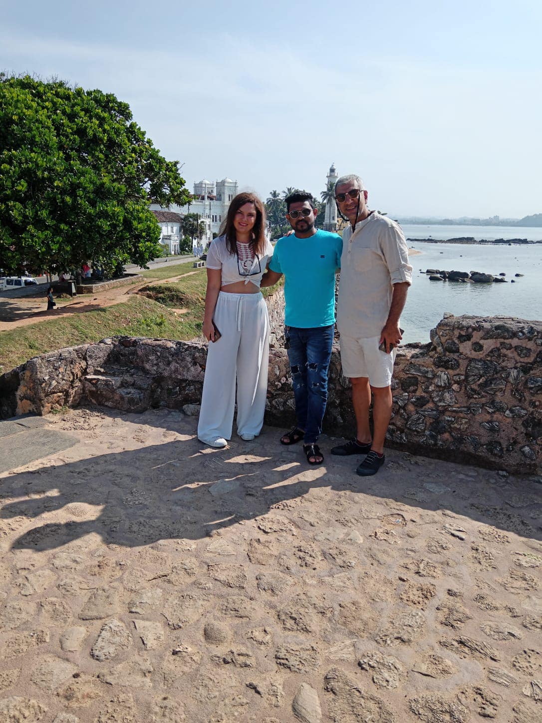 Three travellers standing beside a waterfront wall